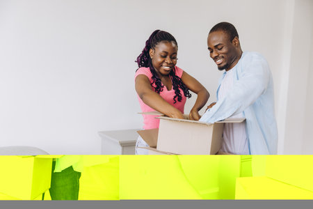 Smiling couple unpacking their belongings from cardboard boxes, enjoying the excitement of moving...
