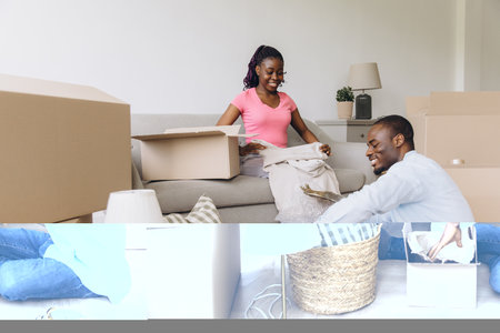 Young black couple unpacking household items from cardboard boxes, arranging furniture and making themselves comfortable in new homeの写真素材