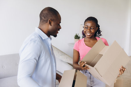 Smiling couple unpacking their belongings from cardboard boxes, joyfully settling into their new home and embracing fresh beginningsの写真素材