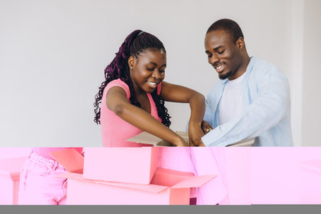 Young smiling african american couple unpacking belongings from cardboard boxes in new apartmentの写真素材