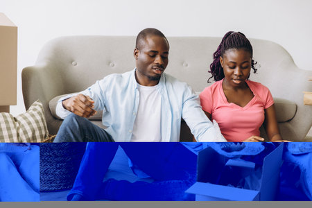 Happy homeowners unpacking belongings from cardboard boxes, creating a cozy atmosphere in their new apartment filled with excitement and joyの写真素材