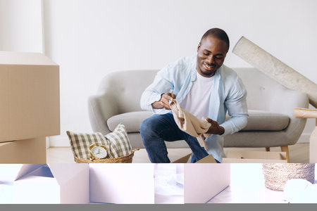 Happy African American man unpacking clothes from a cardboard box in a new apartment, enjoying the excitement of moving into a fresh, cozy homeの写真素材