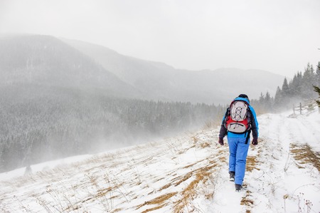 Young woman backpacker traveling in winter mountains