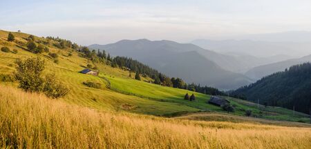 Panorama of beautiful mountains landscape, farm, barns and stacks of hay. Autumn colors. Grassy...