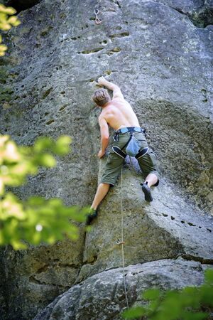 Athletic young male climber climbing on large boulders. outdoor summer dayの写真素材