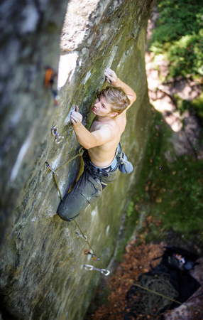 Young athletic man rock-climbing on large boulders. Outdoor summer dayの写真素材