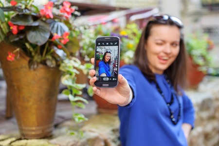 portrait young happy beautiful long-haired brunette lady in blue dress, taking a selfの写真素材