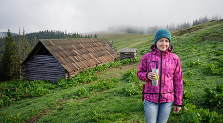 young girl standing with a cup of coffee in the morning in the mountains