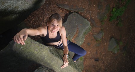 Top view of cute female climber looking up and smiling, rocky background. Summer timeの写真素材