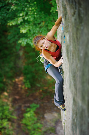 Athletic young girl climber looking for next grip on challenging rock wall. Sport and healthy lifestyle concept. Summer time.の写真素材