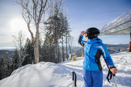 Female skier on the top of ski slope with ski-lift and mountains on the background. Winter sports concept. Woman is looking at beautiful mountain landscape. Carpathian Mountains, Bukovel, Ukraineの写真素材