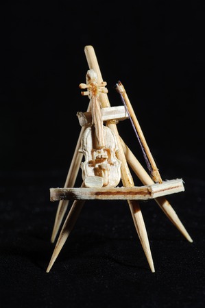 Wooden miniature of violin on black background. Music instrument standing on wooden stand. Macro shot.の写真素材