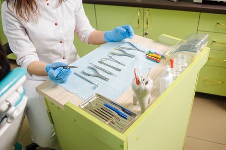 Different dental instruments and tools in a dentist's office. Stomatology clinic. Teeth care and tooth health. Dentist holding dental device for fixing teeth. Orthodontic Treatmentの写真素材