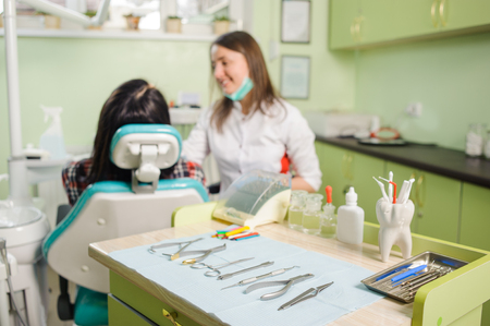 Dental instruments and tools on the foreground and female doctor dentist with patient on the background in a dentist's office. Orthodontic Treatmentの写真素材