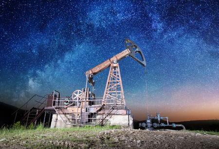 Oil industry equipment pumping crude oil in the night under Milky wayの写真素材