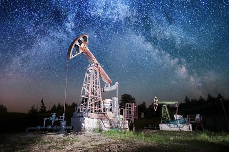 Two oil pumps are working on the oil field, oil industry equipment. Milky way shines aboveの写真素材