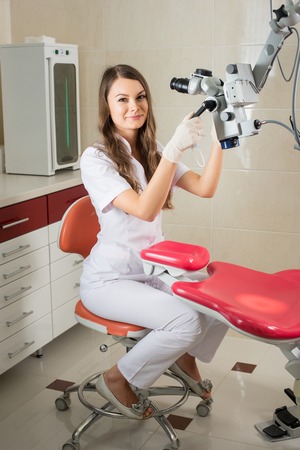 Attractive female doctor in gloves with microscope at work in the modern dentist office.の写真素材