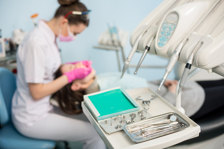 Different professional dental instruments, on the blurred background dentist is treating patient in dental clinic. Selective focus. Dentistryの写真素材