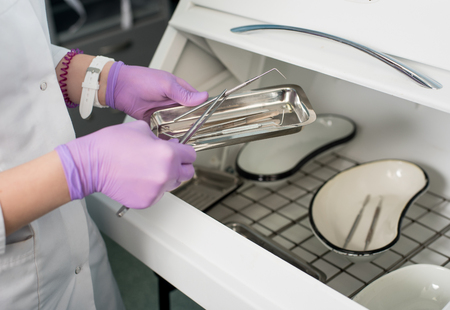 Dentist with gloved hands is working with dental equipment in dental office. Close-upの写真素材