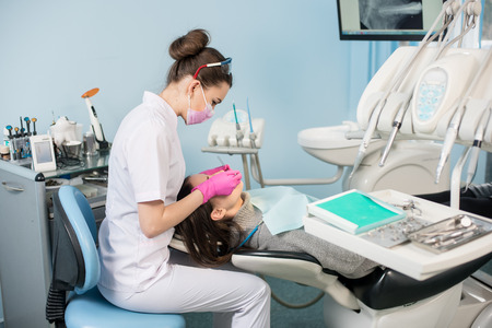 Female dentist with dental tools - mirror and probe checking up patient teeth at dental clinic office. Medicine, dentistry and health care concept. Dental equipmentの写真素材