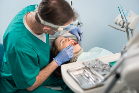 Male dentist with dental tools - mirror and probe checking up patient teeth at dental clinic office. Medicine, dentistry and health care concept. Dental equipmentの写真素材