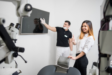 Male dentist showing dental x-ray image on computer monitor in a dental clinic. Female patient is smiling and showing thumbs up. Focus on a woman. Dentistryの写真素材