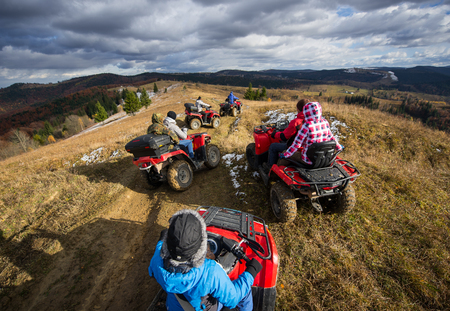 Top view of a group of people riding a off-road vehicles on a mountain road under a sky with clouds in autumnの写真素材