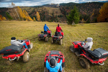 Group of people riding a quad bikes on hill. Beautiful landscape of mountains and colorful forest under the sky with cumulus clouds in autumn. Top viewの写真素材