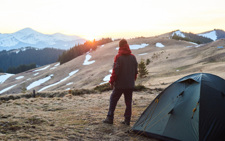 Evening camping. Rearview shot of a man standing near his tent in the mountains looking around copyspace lifestyle tourism travelling hiker sportive tripの写真素材