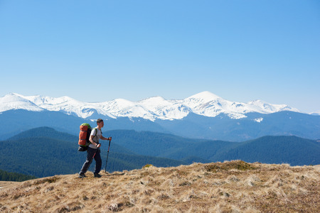 Full length shot of a man tourist with a backpack admiring the view walking on top of the mountain using hiking sticks copyspace achieving equipment athletic sportive lifestyle activeの写真素材