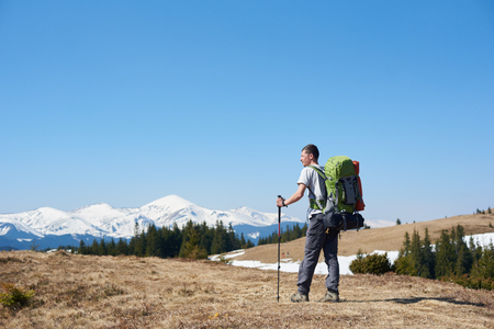 Rearview of an adventurous man with hiking equipment using trekking sticks while walking the mountain copyspace travelling adventure nature landscape sport activityの写真素材