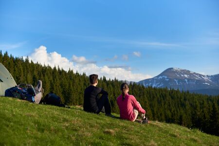 Rearview shot of two women sitting on top of a hill near their tent enjoying beautiful mountains view copyspace lifestyle activity sport health friendship travellingの写真素材