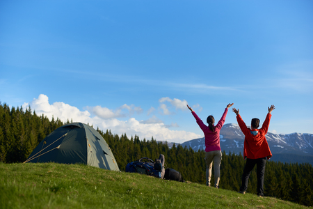 Rearview shot of two happy female hikers embracing morning sun on top of a hill standing with their arms outstretched happiness emotions friendship lifestyleの写真素材