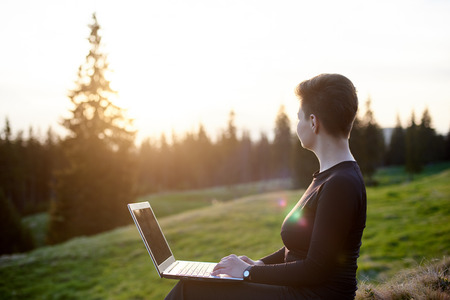 Horizontal shot of a woman using laptop outdoors sitting on top of a hill copyspace online technology 3g 4g wireless connectivityの写真素材