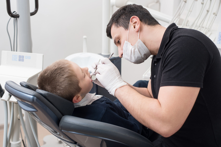 Pediatric dentist examining teeth of boy patient in dental clinic using dental tools - probe and mirror. Dentistryの写真素材