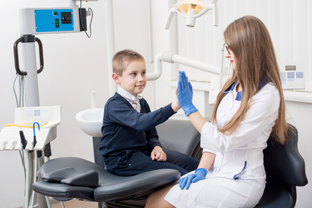 Smiling kid giving five to female dentist in dental clinic. Young boy on dental check upの写真素材