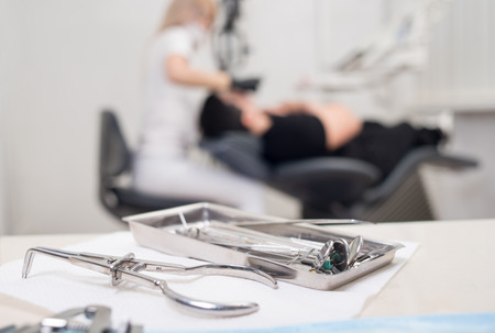 Different professional dental instruments, on the blurred background dentist is treating patient at the dental clinic. Selective focus. Stomatologyの写真素材