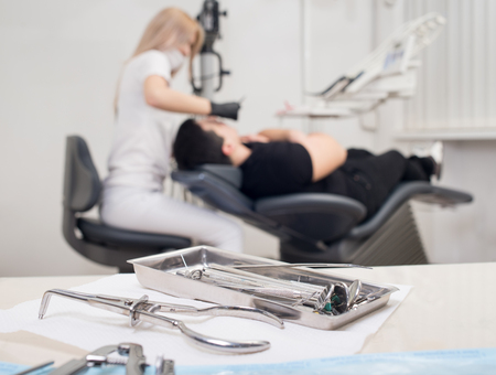 Different professional dental instruments, on the blurred background dentist is treating patient at the dental office. Selective focus. Dentistryの写真素材