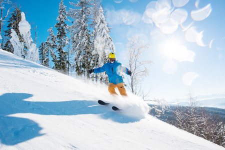 Shot of a male freerider skiing in the mountains on fresh powder snow on a beautiful sunny winter dayの写真素材