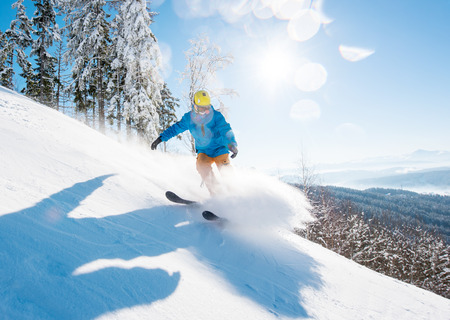 Shot of a professional skier skiing in the mountains on fresh powder snow on a beautiful sunny winter day on the winter resortの写真素材