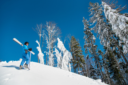 Shot of a woman skier enjoying beautiful view of snowy mountains while walking up the slope carrying her skis on the shoulder copyspace winter freeride downhill extremeの写真素材