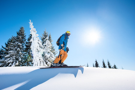 Low angle and full length shot of a skier on top of the mountain enjoying beautiful sunny winter day copyspace active people living leisure hobby extreme slope snow seasonal sportの写真素材