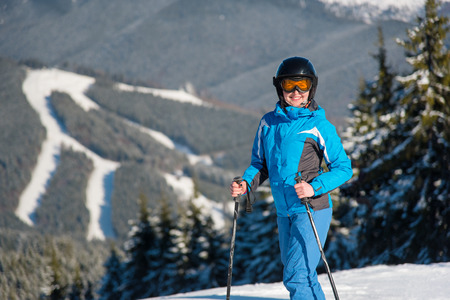 Shot of a female skier smiling to the camera joyfully while skiing in the mountain on a sunny winter day beautiful landscape, forests, ski slopes on the background copyspaceの写真素材