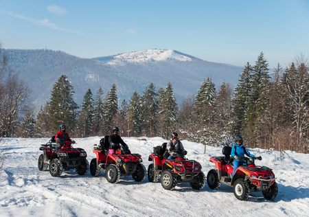Four ATV riders on off-road quad bikes at top of the mountain in winterの写真素材