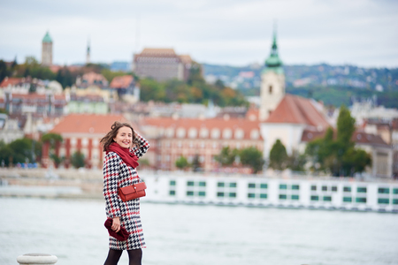 Close-up of girl walks along the embankment of Budapest with blurred view of Buda side of Budapest with the Buda Castle, St. Matthias and Fisherman's Bastion. Her hair is blown by the wind.の写真素材