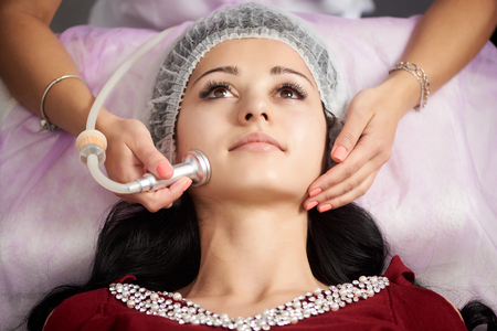 Cosmetology and skin care routine. Beautiful female patient is having a procedure of microdermabrasion in a beauty salon.の写真素材