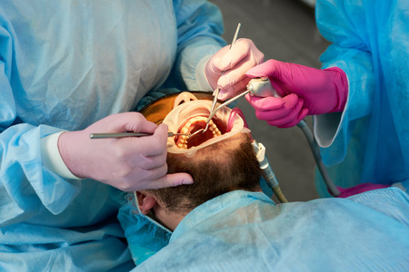 Close-up of a man with a beard during a reception at a dentist. Dentist with an assistant in a...