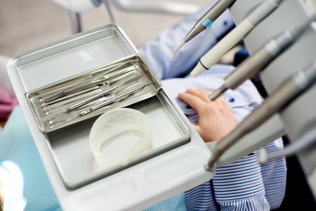 Dental instruments are being displayed on a silver medical tray in a dental office.の写真素材