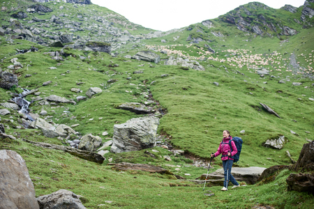 Young woman tourist walking down the hill hiking in the mountains copyspace season nature exploring travelling tourism lifestyle landscape view scenery layout backgroundの写真素材