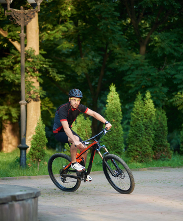 Sporty male cyclist in sportswear training on bike, riding paved park alley. Muscle sportsman getting ready for contest. Concept of healthy lifestyleの写真素材